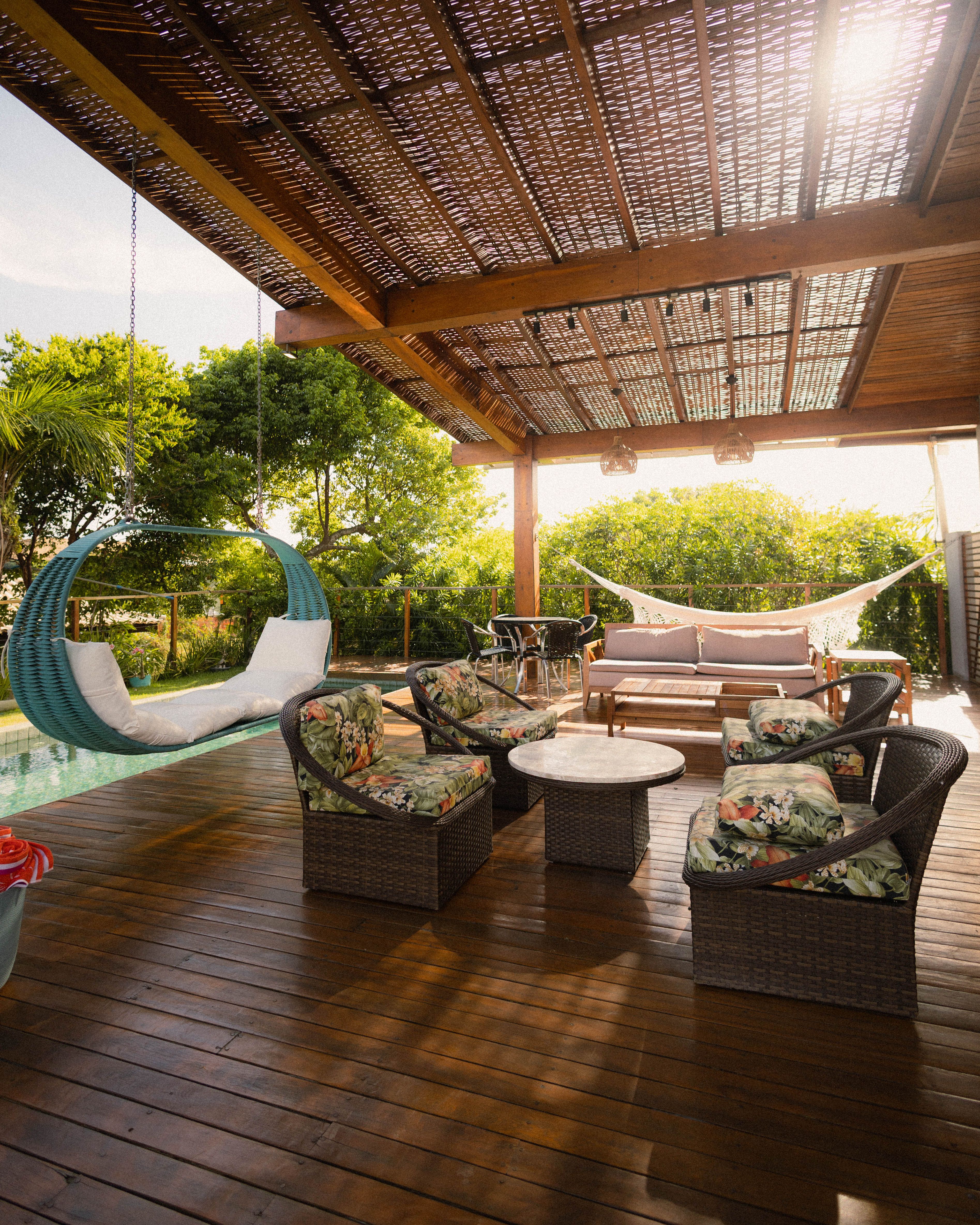 A serene outdoor patio with lush garden, wooden decking, and hammock seating.
