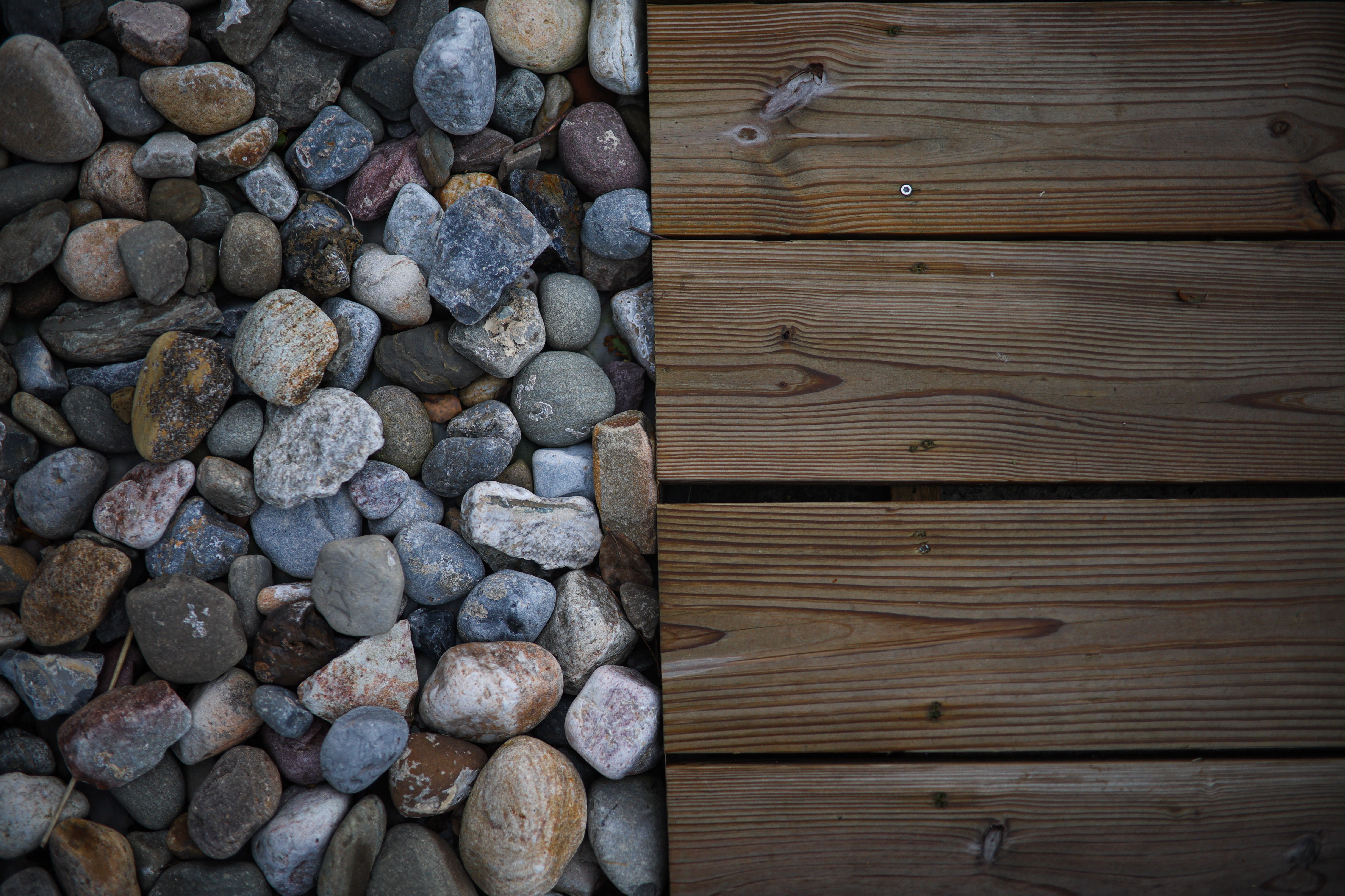 Aerial view of assorted stones next to wooden deck planks, showcasing textures.